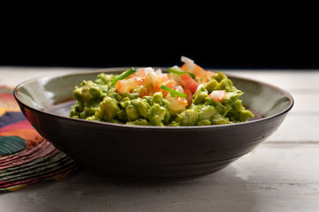 Traditional mexican guacamole with tomato and serrano pepper on white backgroundの写真素材