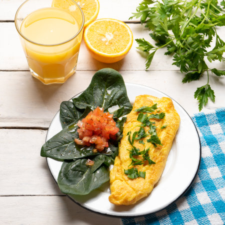 French egg omelette with tomato and spinach on white backgroundの写真素材