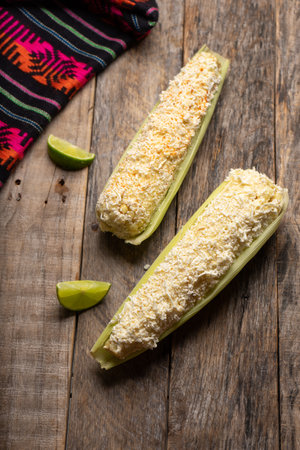 Traditional mexican boiled corn on the cob with mayonnaise and cheese on wooden backgroundの写真素材