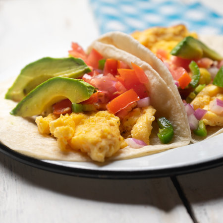 Traditional breakfast egg tacos with flour tortilla and fresh sauce on white backgroundの写真素材