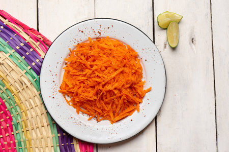 Traditional mexican grated carrot with lime and chili powder on white backgroundの写真素材