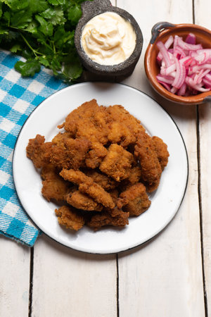 Fried fish chicharron with mayonnaise and onion on white background