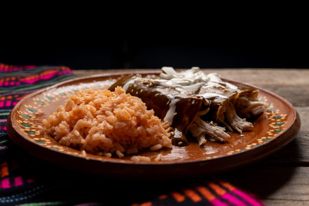 Traditional mexican chicken enchiladas with mole sauce and rice on wooden backgroundの写真素材