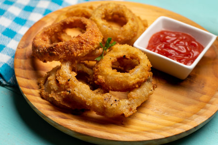 Fried onion rings with ketchup on turquoise backgroundの写真素材