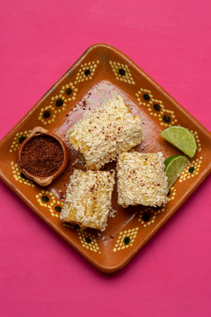 Traditional mexican corn on the cob also called elotes with cheese and mayonnaise on pink backgroundの写真素材