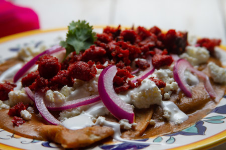 Traditional mexican enfrijoladas with chorizo and cheese on white background