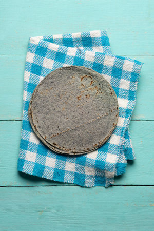 Traditional mexican blue corn tortilla on turquoise backgroundの写真素材