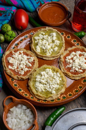 Traditional mexican picaditas with sauce and fresh cheese on wooden backgroundの写真素材