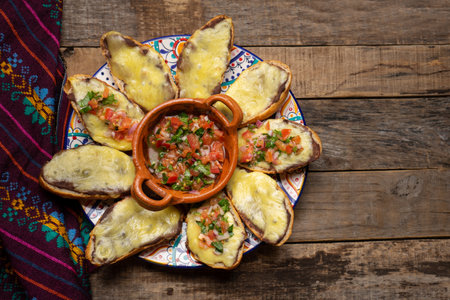 Traditional mexican molletes with cheese and fresh sauce on wooden backgroundの写真素材