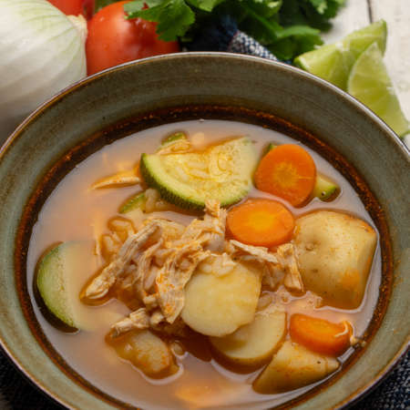 Traditional chicken soup with rice and vegetables on white backgroundの写真素材