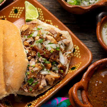 Confit pork sandwich called Torta de carnitas on wooden background. Traditional Mexican foodの写真素材