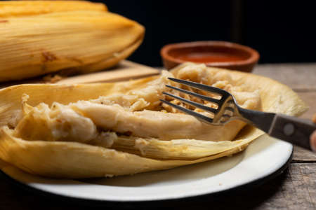 Traditional chicken Tamal with green sauce in corn leaf on wooden background. Mexican foodの写真素材