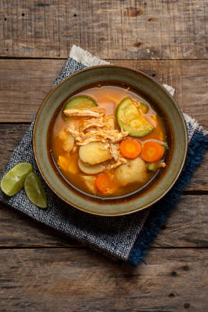 Traditional chicken soup with rice and vegetables on wooden backgroundの写真素材