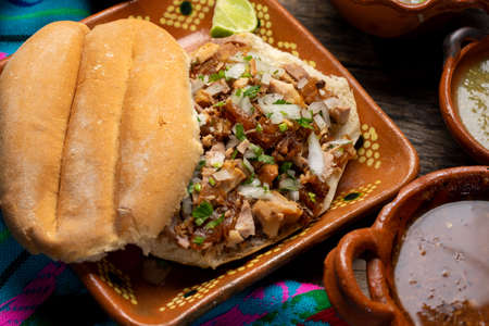 Confit pork sandwich called Torta de carnitas on wooden background. Traditional Mexican foodの写真素材