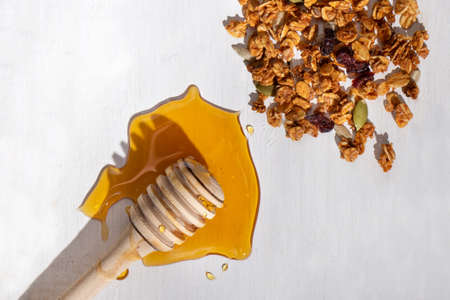 Wood honey dipper stick and muesli on white background