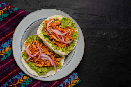 Chicken tinga tacos with guacamole and onion on dark background. Traditional mexican foodの写真素材