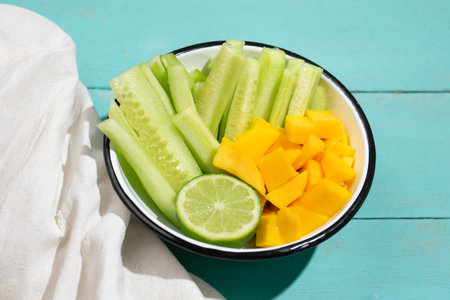 Fresh cucumber and mango salad on turquoise backgroundの写真素材