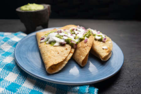 Fried tacos with guacamole and sour cream on dark background. Traditional mexican foodの写真素材