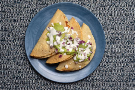 Fried tacos with guacamole and sour cream on blue background. Traditional mexican foodの写真素材