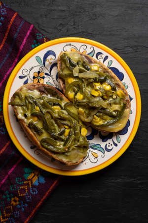 Molletes with poblano rajas and cheese on dark background. Traditional mexican foodの写真素材