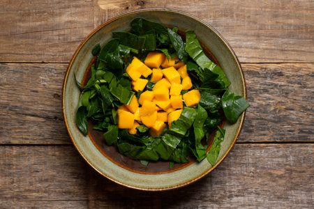 Fresh spinach and mango salad on wooden background