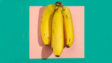 yellow bunch of bananas on pink background