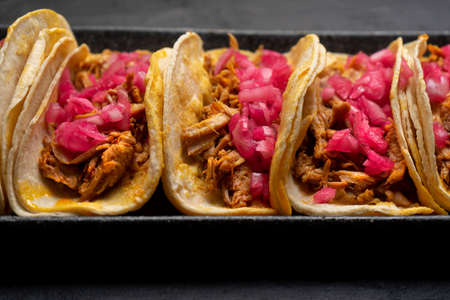 Pork tacos called cochinita pibil with purple onion on dark background. Traditional mexican tacosの写真素材