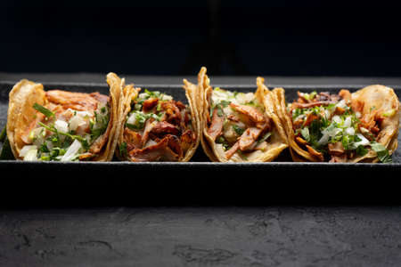 Pork tacos called al pastor with pineapple on dark background. Traditional mexican tacos