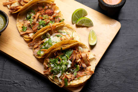 Pork tacos called al pastor with pineapple on dark background. Traditional mexican tacosの写真素材