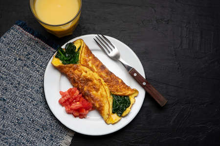 Egg omelette with spinach and tomato on dark background. Tradtional french foodの写真素材