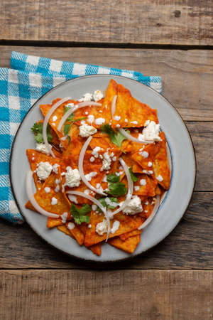 Traditional mexican food. Red chilaquiles with cheese and sour cream on wooden backgroundの写真素材