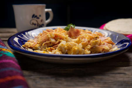 Traditional scrambled eggs with ham for breakfast on wooden backgroundの写真素材