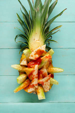 Fresh cucumber, jicama and pineapple with chili powder and chamoy sauce on turquoise background. Mexican snackの写真素材
