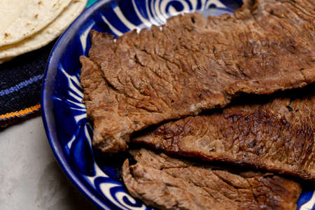 Beef steak called tampiqueÃ±a with cactus and onion on a gray background. Traditional mexican food