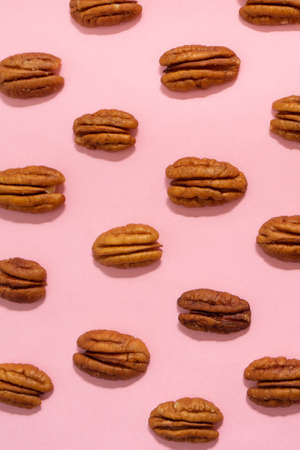 Peeled walnuts creating a pattern on a pink background