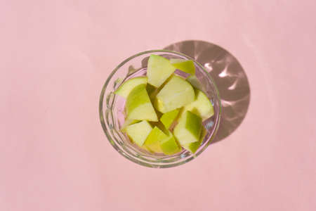 Fresh apple cut inside a glass container on a pink backgroundの写真素材