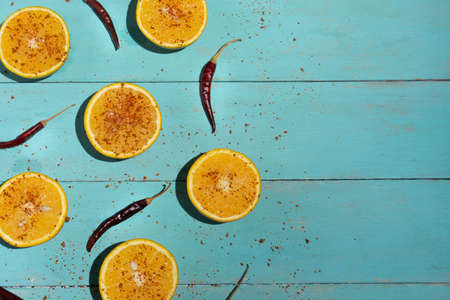 Fresh orange halves with chili pepper powder on turquoise backgroundの写真素材