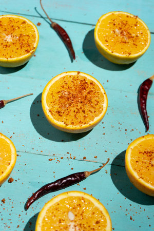 Fresh orange halves with chili pepper powder on turquoise backgroundの写真素材