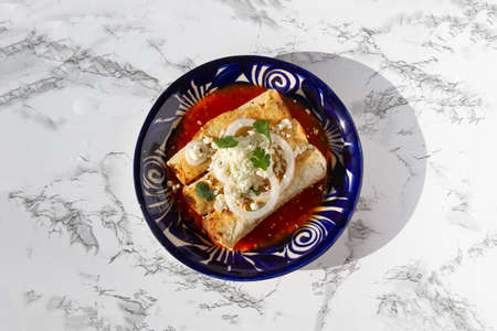 Fried potato tacos called flautas with red sauce and cheese. traditional mexican foodの写真素材