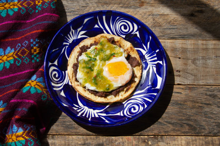 Mexican green ranchero eggs on tortilla toast and refried beans.の写真素材