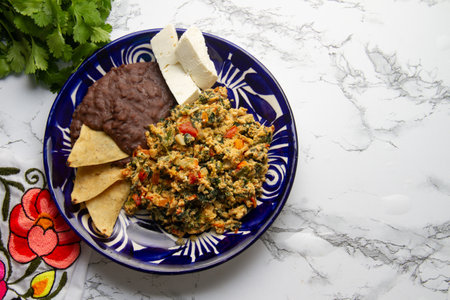 Experience Yucatecan cuisine with our Huevo con Chaya. Scrambled eggs with indigenous chaya, succulent tomatoes, onion, refried beans, and fresh cheese. A nutritious and flavorful meal.の写真素材