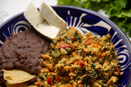 Experience Yucatecan cuisine with our Huevo con Chaya. Scrambled eggs with indigenous chaya, succulent tomatoes, onion, refried beans, and fresh cheese. A nutritious and flavorful meal.の写真素材