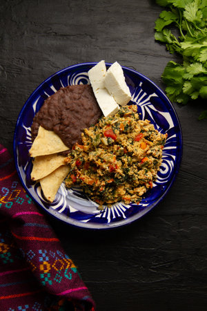 Experience Yucatecan cuisine with our Huevo con Chaya. Scrambled eggs with indigenous chaya, succulent tomatoes, onion, refried beans, and fresh cheese. A nutritious and flavorful meal.の写真素材