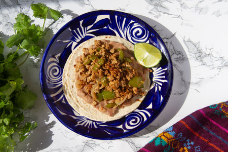Mouthwatering tacos featuring seasoned ground pork, sautÃ©ed peppers, onions, tomatoes, and a bed of refried beans on corn tortillas.の写真素材