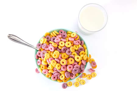 A top view of multicolored fruity cereals and glass milk isolated on a white background