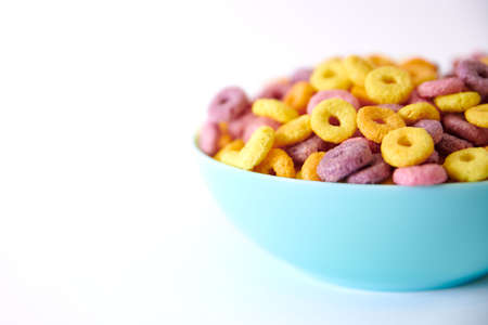 A closeup shot of multicolored fruity cereals and glass milk isolated on a white backgroundの写真素材