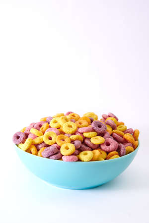 A closeup shot of multicolored fruity cereals and glass milk isolated on a white backgroundの写真素材