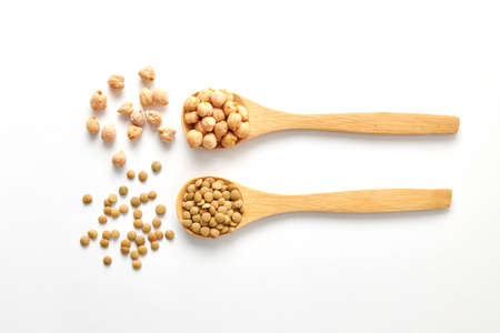 A top view shot of dried lentils, chickpeas with wooden spoons isolated on white backgroundの写真素材