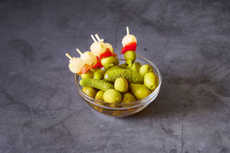 A glass bowl with Spanish brochettes on a black slate backgroundの写真素材