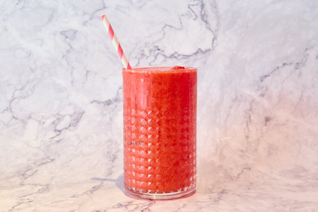 Glass of watermelon smoothie with straw on white marble background.の写真素材